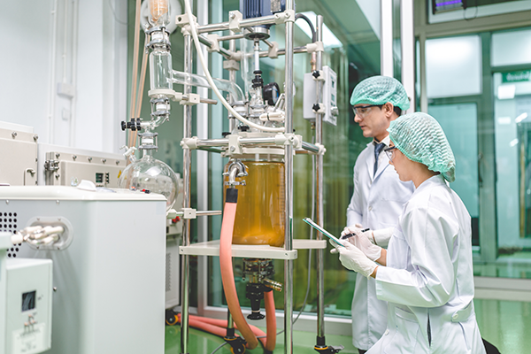 Two scientists in a lab looking at a bioreactor