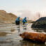 Two ecologists in rubber gloves, protective coveralls, eyeglasses and respirators studying characteristics of toxic water in dangerous area